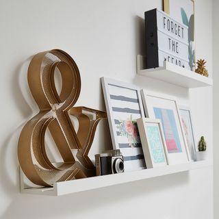 frames camera and showpieces on white wall shelf