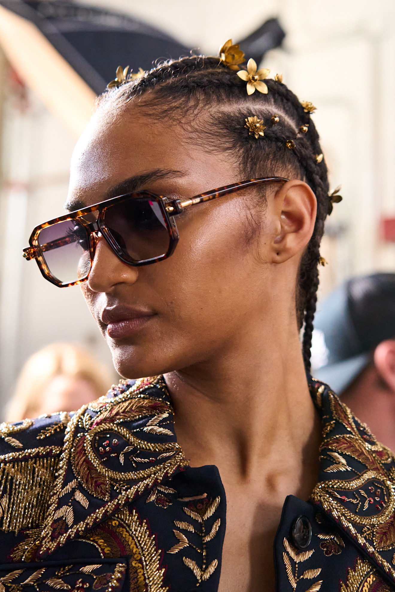model with cornrows decorated with small gold floral hair clips