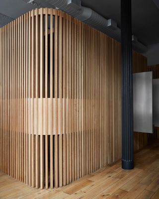 Curved semi-transparent wooden structure and black column at Spiral (x,y,z)