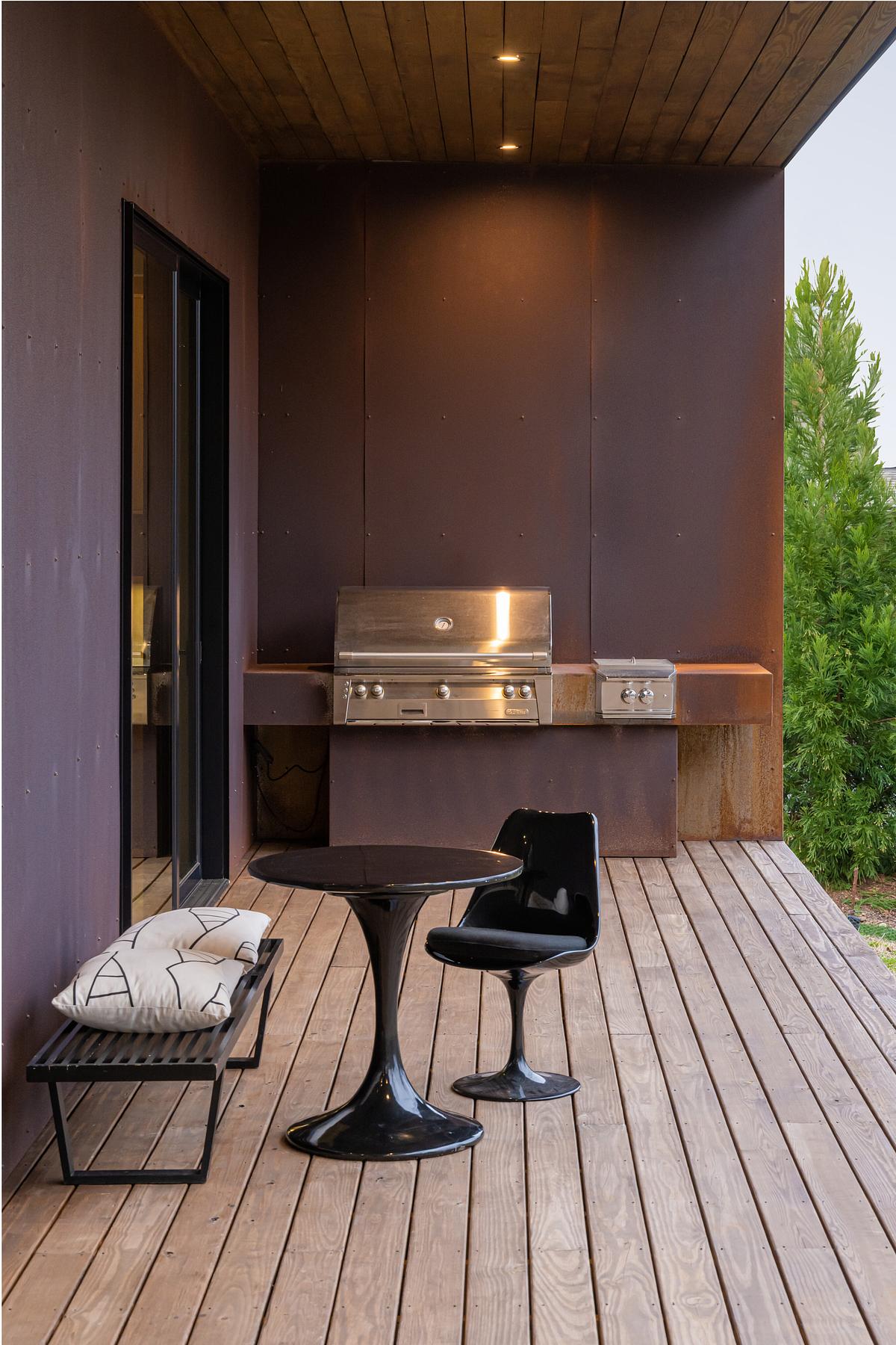 deep aubergine painted outdoor kitchen with wooden floors and a small black, glossy dining area