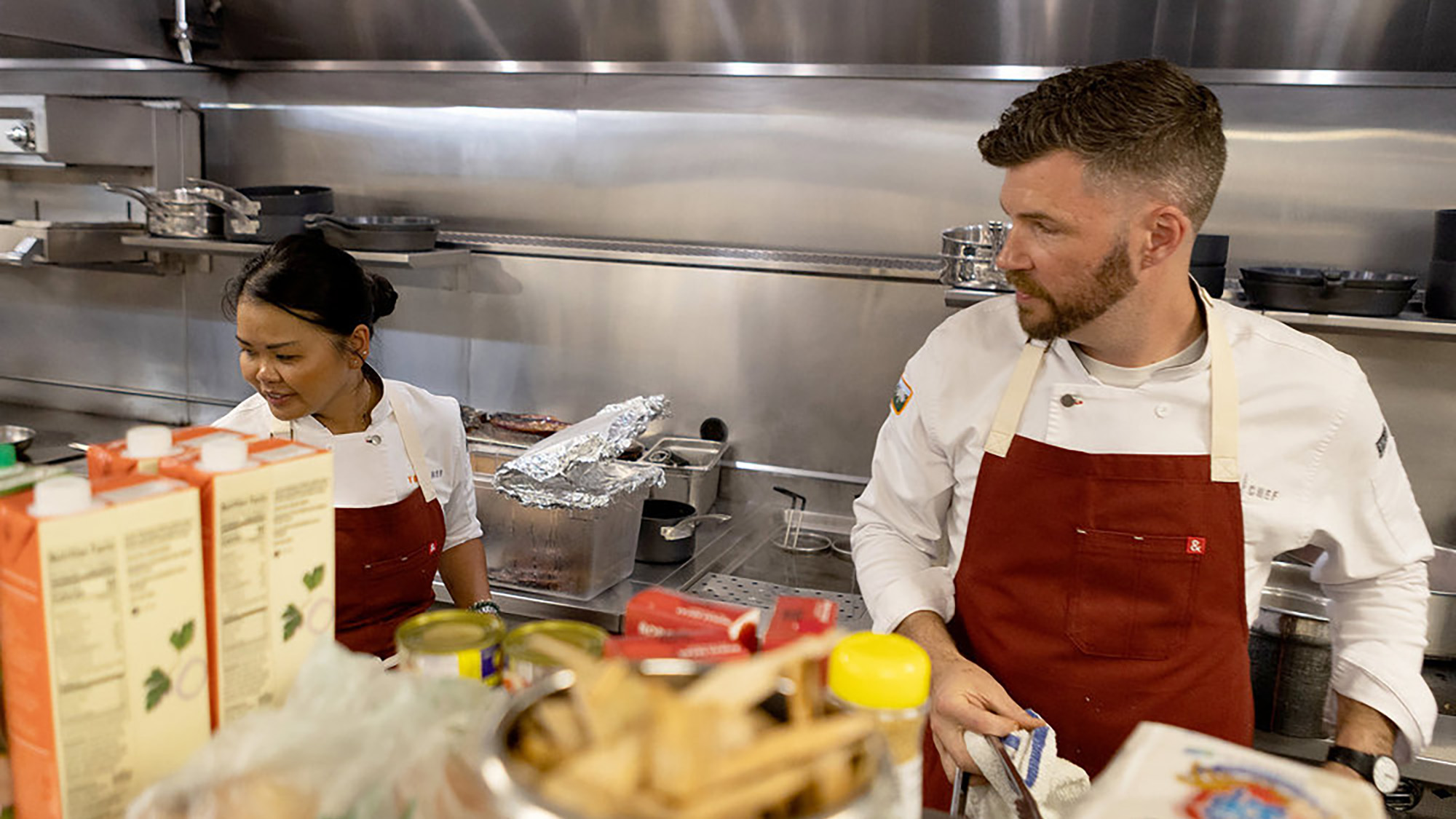 Rhoda and Sieger cook together in red aprons during the Top Chef Season 23 finale.