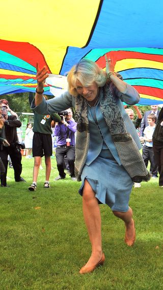 Queen Camilla running under a colourful parachute