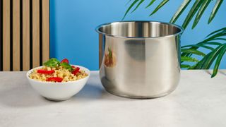 a black pressure cooker photographed against a blue background, showing its cooking presets, steam release valve, and Instant Pot branding