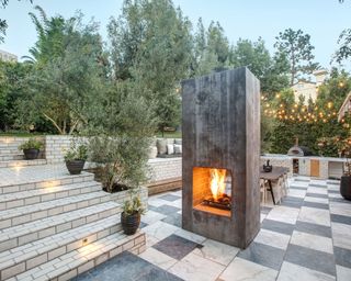 a monolithic fire pit serves to divide the backyard landscaping ideas into different sections