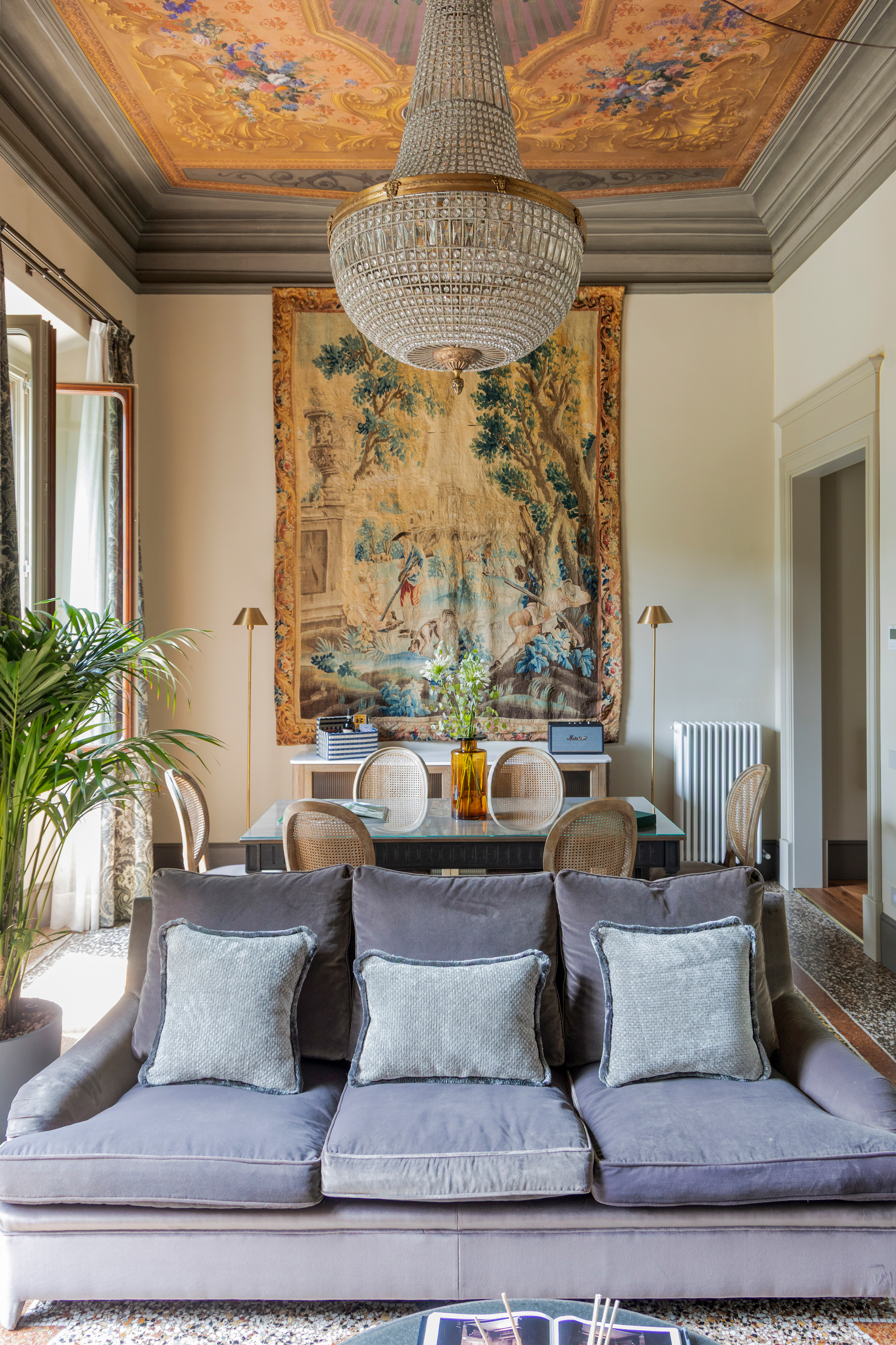 An ornate, palatial residence filled with sunshine, frescoed walls, terrazzo floors, vintage, modern, and plush contemporary furnishings, and thriving plants, whether indoors or on its terrace.