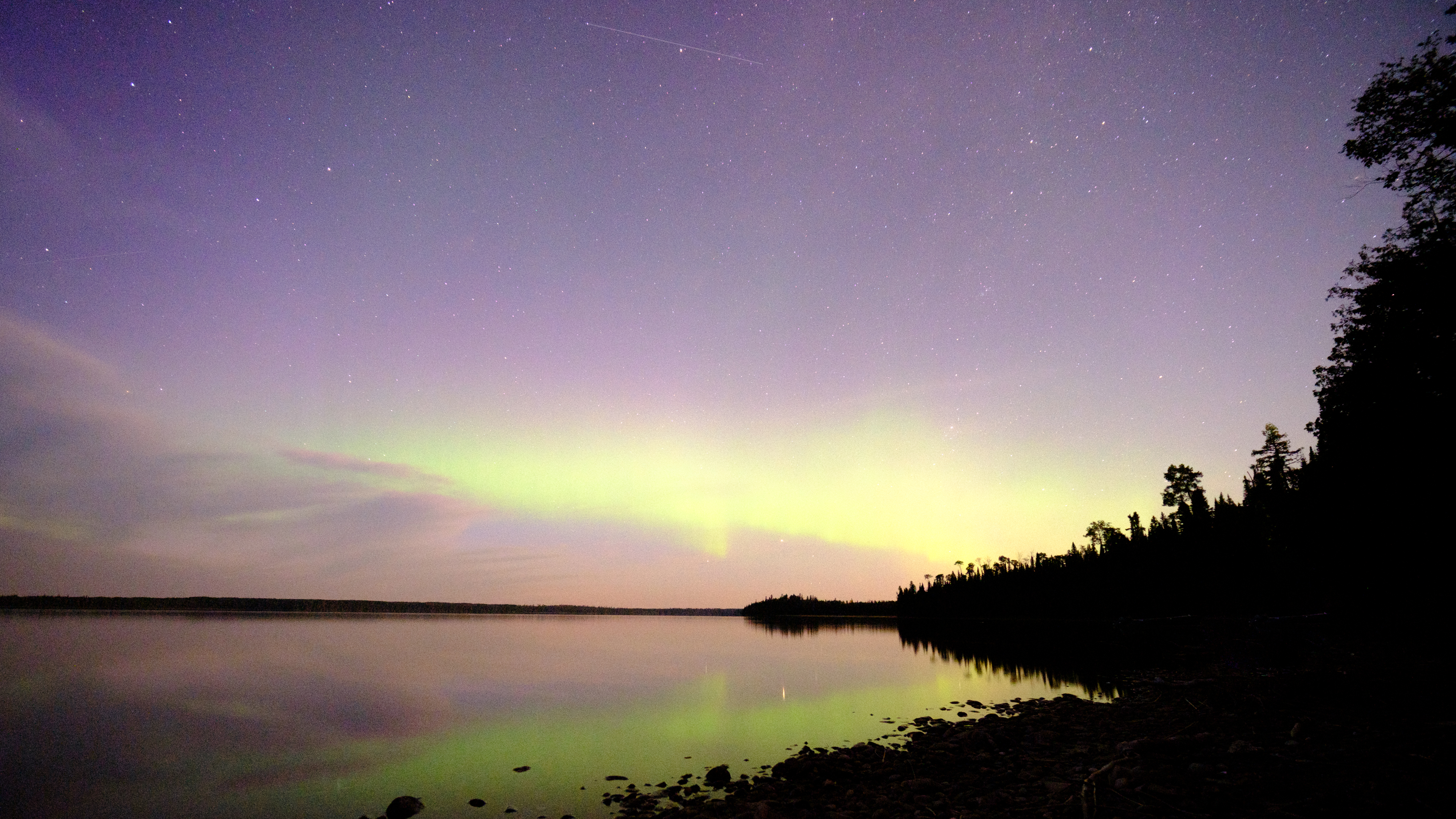 The northern lights reflected over a lake with a Perseid meteor in the frame