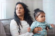 Concerned-looking mother holding baby daughter on the sofa