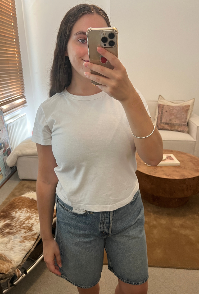 An image of Who What Wear fashion writer Ava Gilchrist wearing a pair of COS denim shorts, one of the best denim shorts for women in 2026.