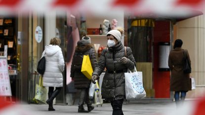 A woman wearing a protective face mask walks through Vienna
