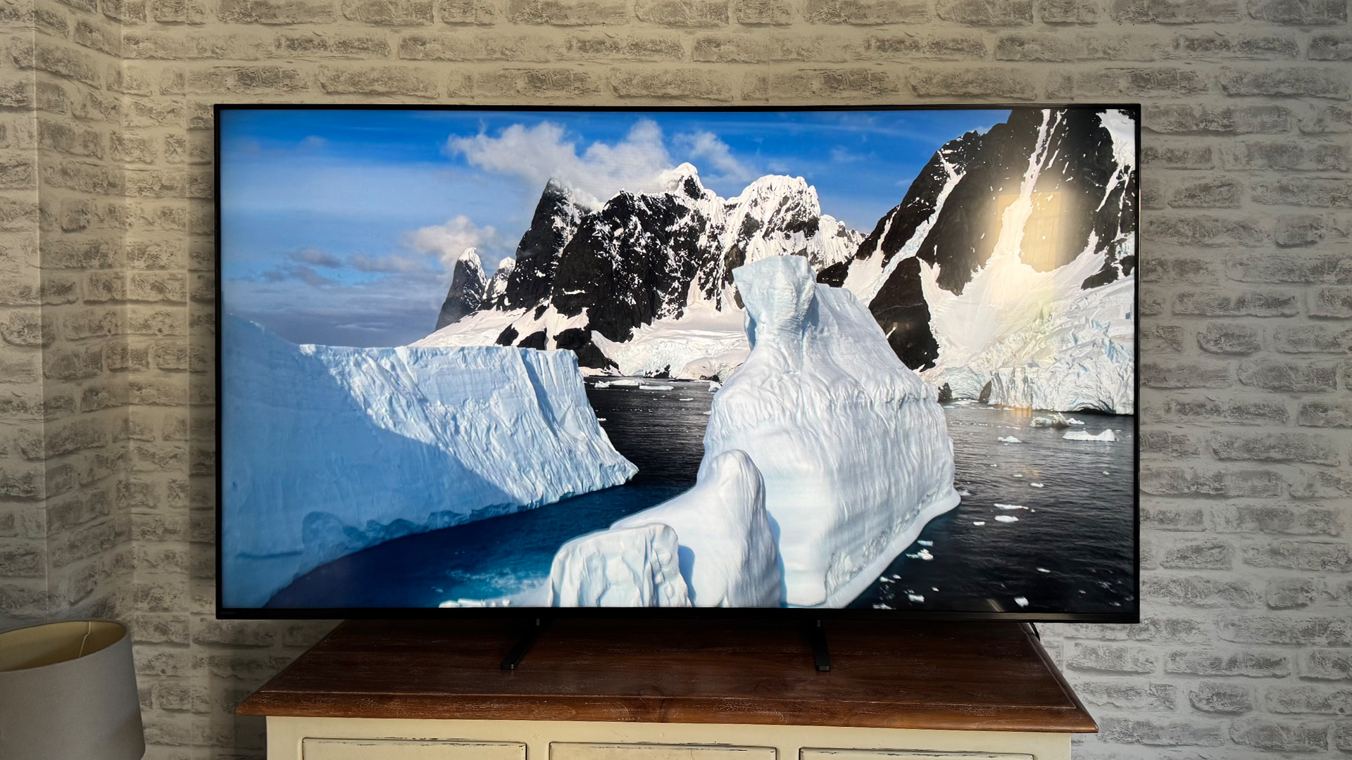 Sony Bravia 5 4K TV on wooden sideboard in front of brick wall, on screen are icebergs