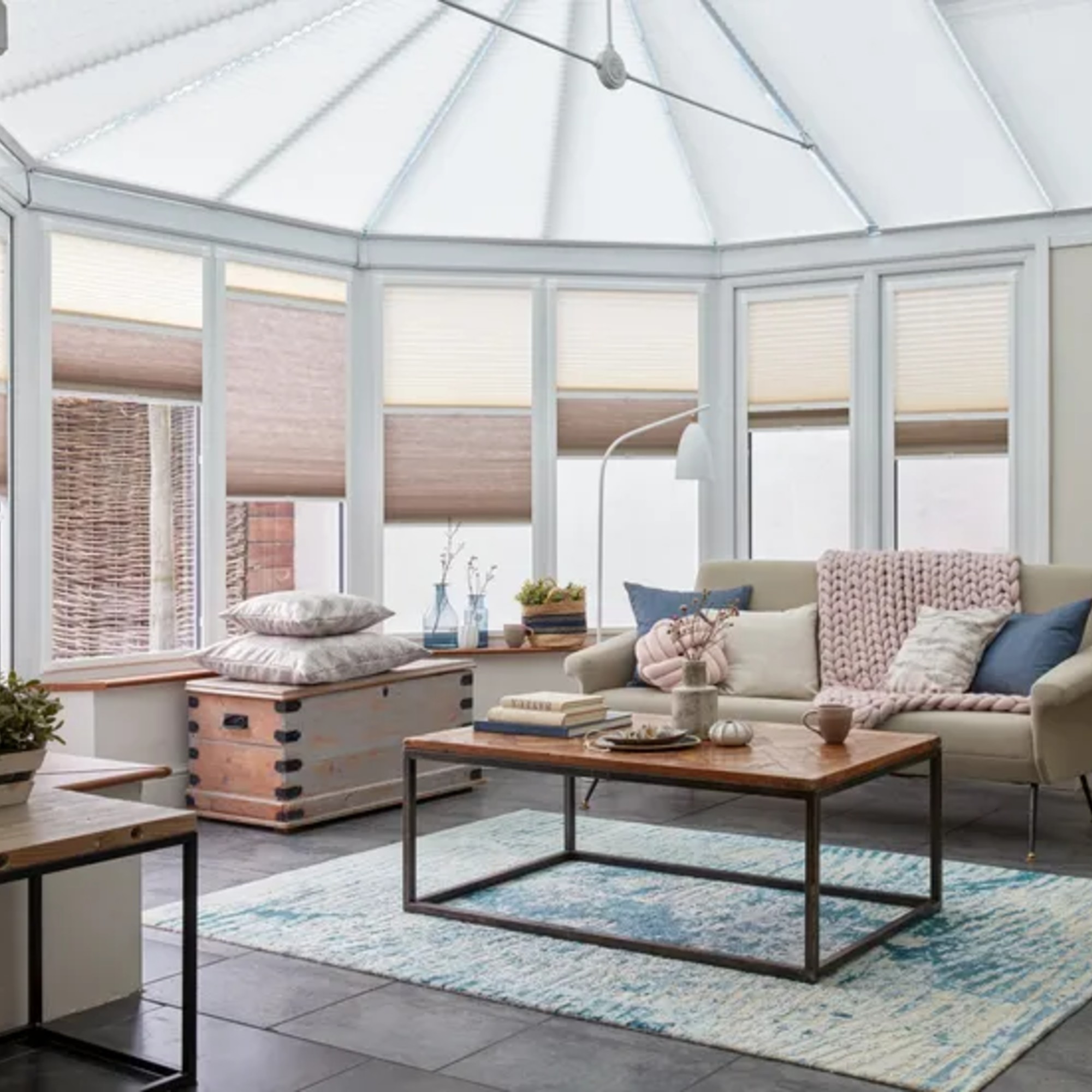 A spacious conservatory with the windows covered in two-toned transition blinds by Hillarys