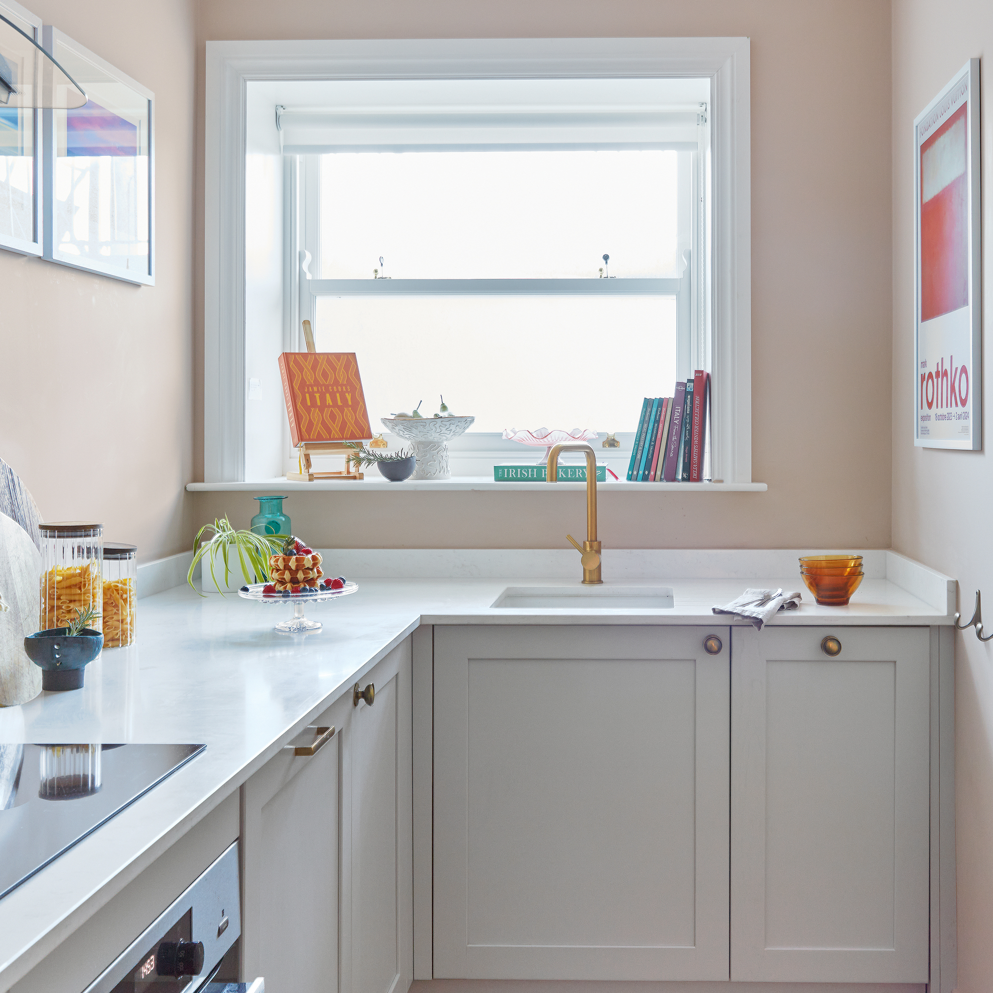a small kitchen with neutral cabinetry and pops of colour from artwork and decor