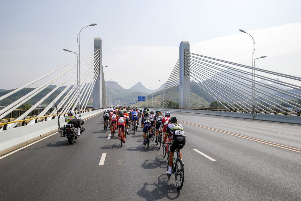 The peloton crosses a bridge at speed