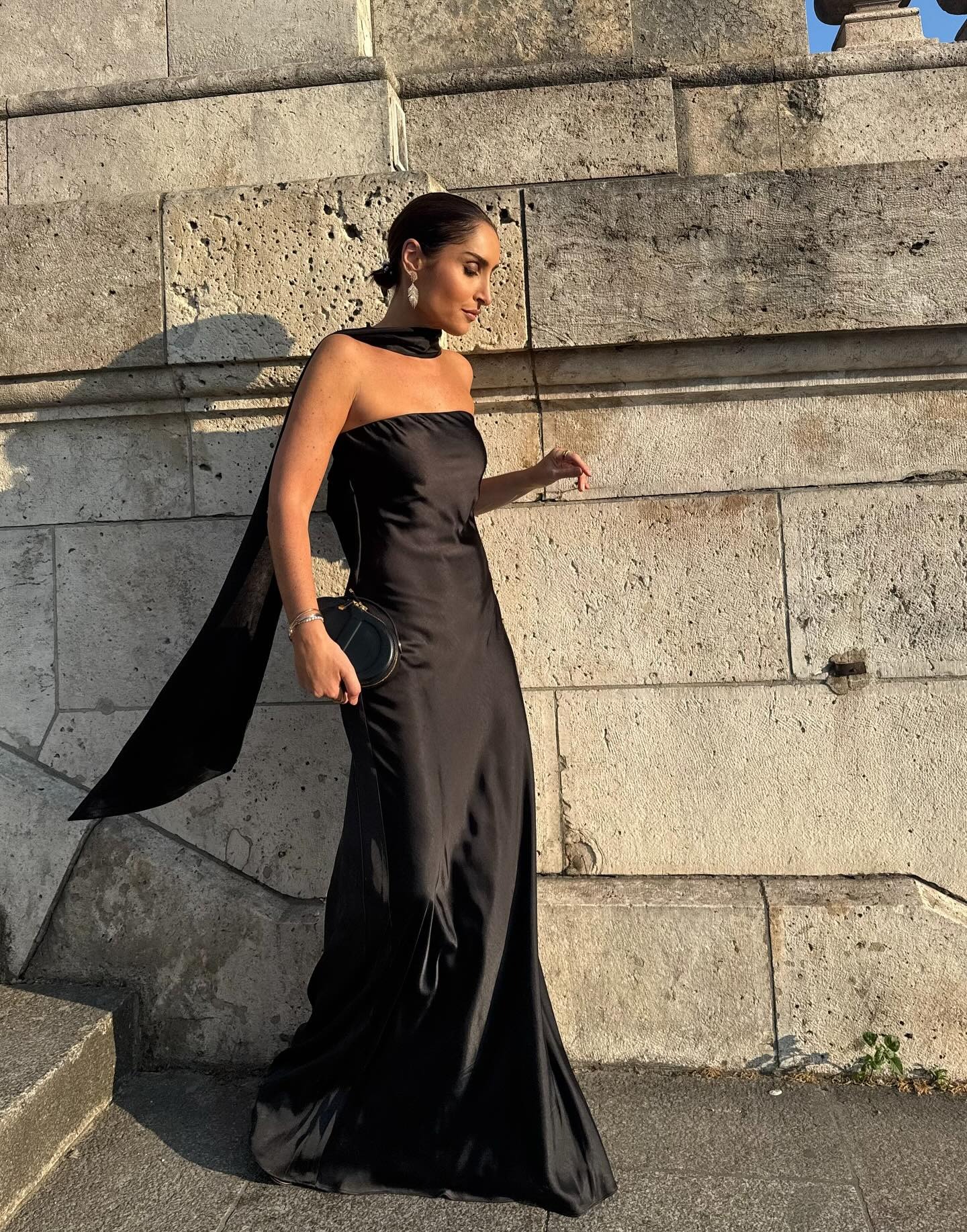A woman wearing a black evening dress with her bob styled into a slicked-back bun