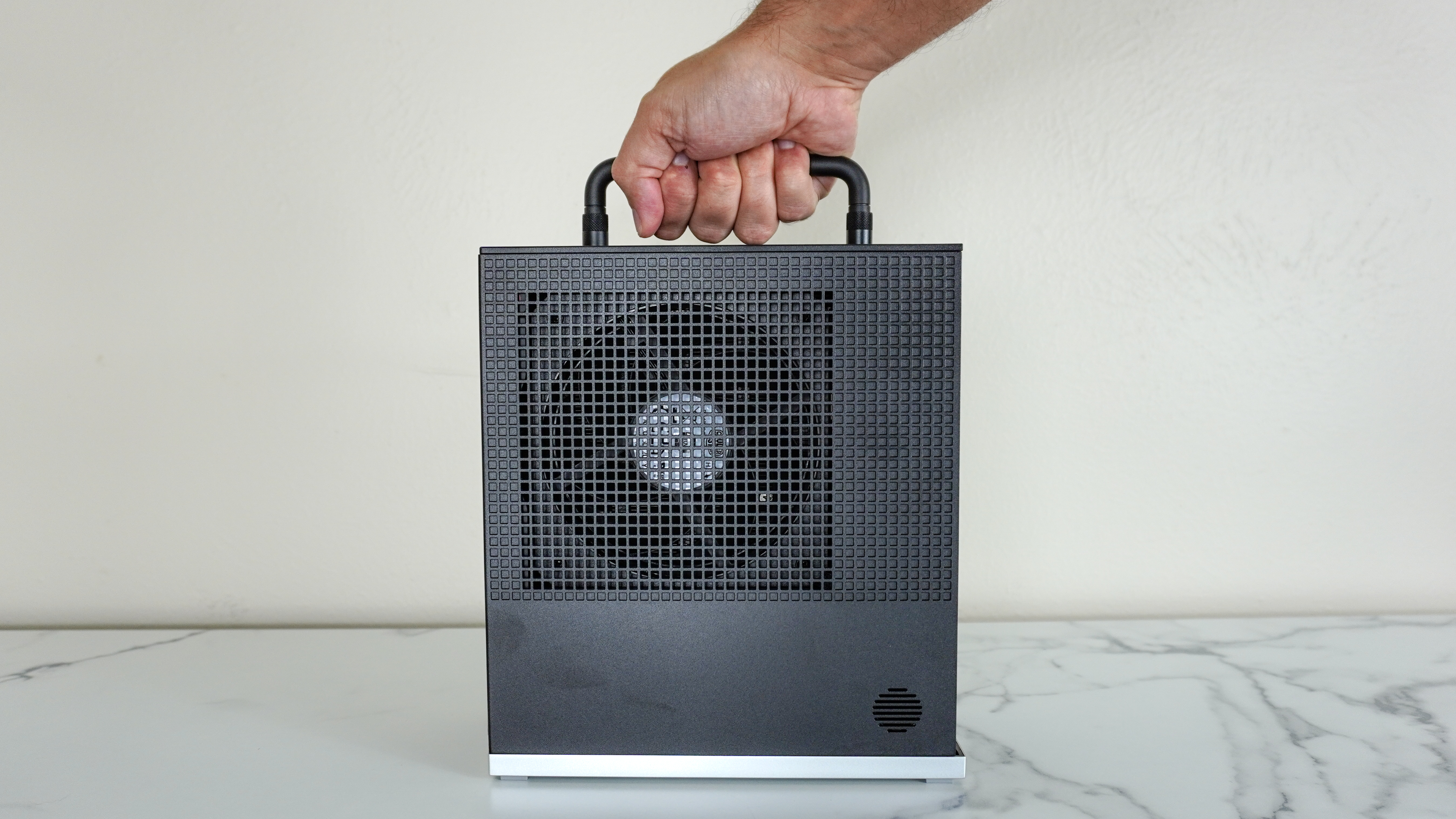 Holding the Framework Desktop by its optional top handle