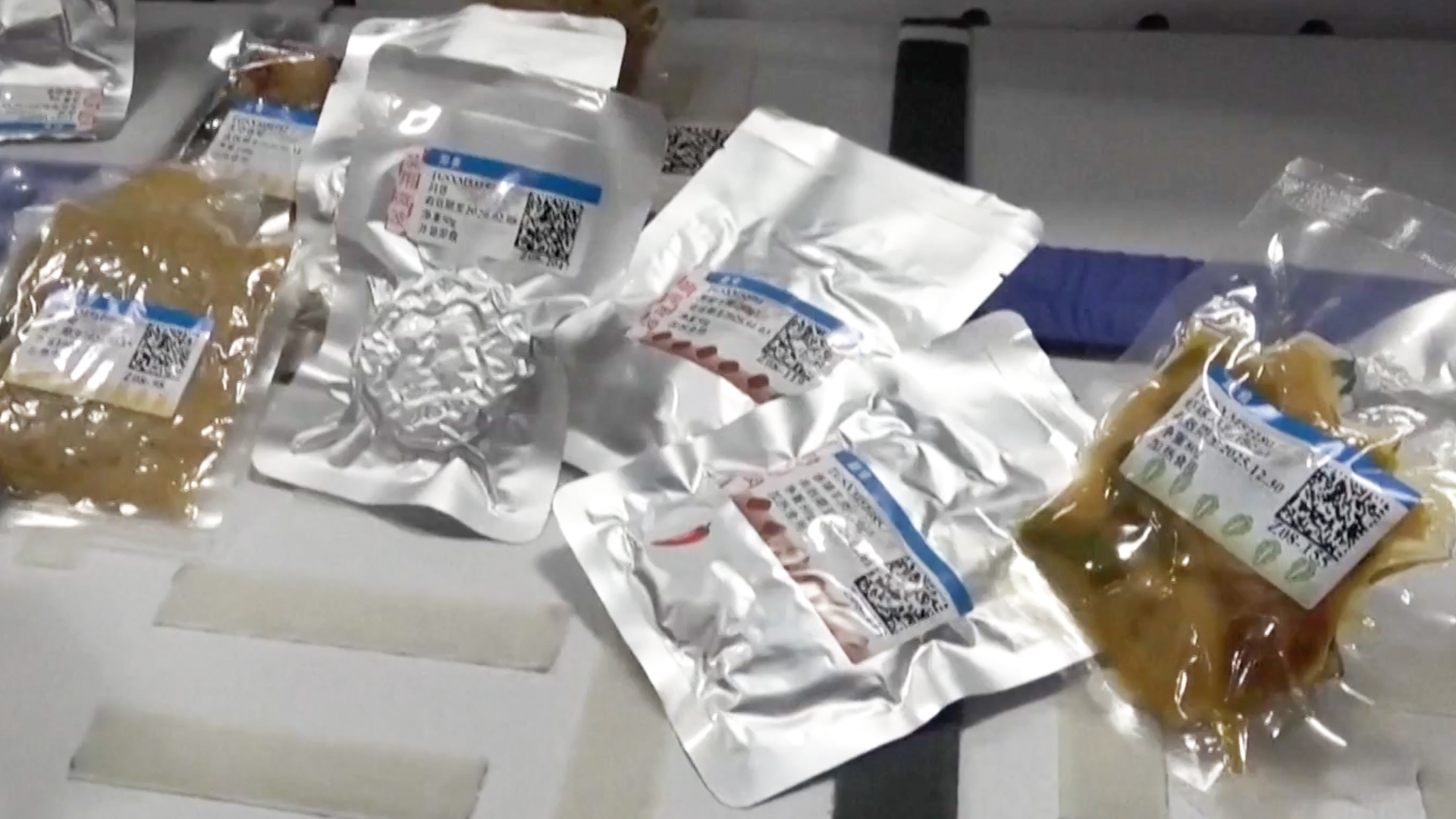 藍色航班上的人們穿著西裝，在狹小的長方形實驗室裡打開鋁箔包裝的食品包裝。