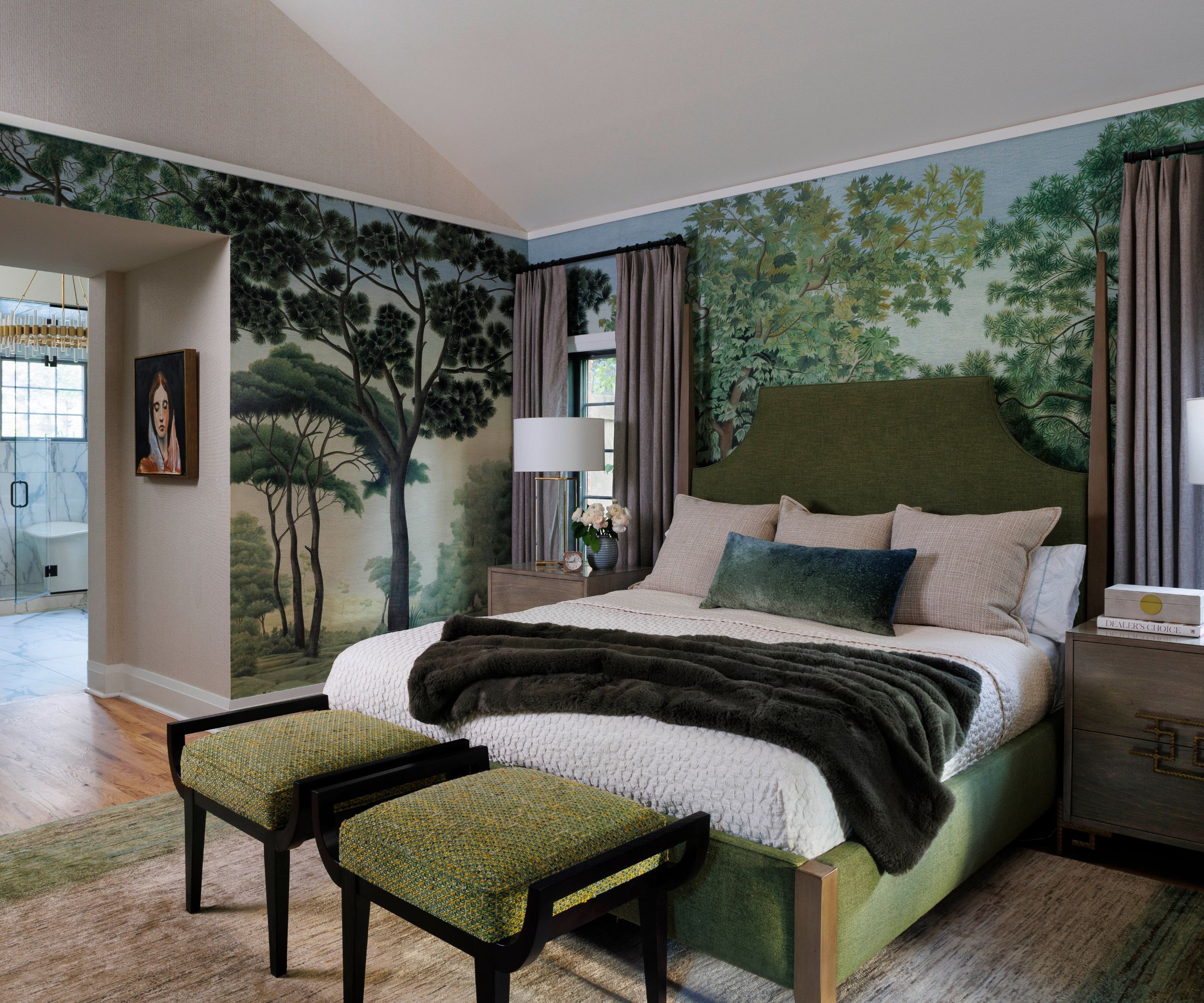 Bedroom with forest print wallpaper and bed with velvet green headboard and two green upholstered stools at the bottom of the bed