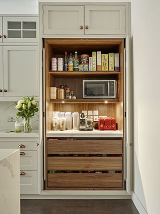 large pantry with in-cupboard lighting in a large white kitchen