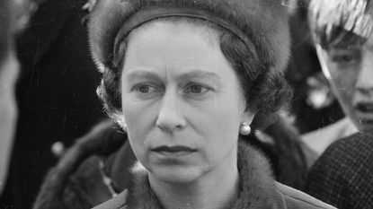 A black and white photo closeup of Queen Elizabeth wearing a fur hat and pearl earrings 