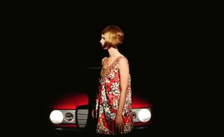Photograph of woman with red dress and car