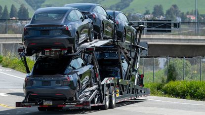 trailer hauling loads of black Teslas