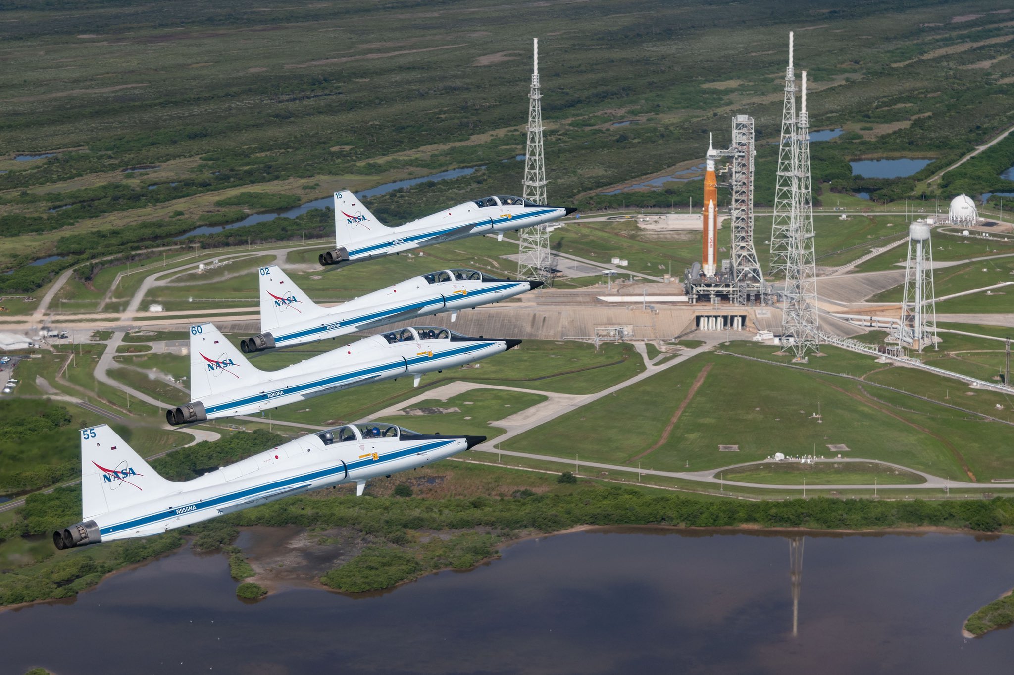 Four T-38 Talons fly by NASA's Space Launch System Block 1 rocket at Kennedy Space Center.
