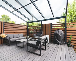 Outdoor terrace with a comfortable outdoor sofa and chairs next to a private building.