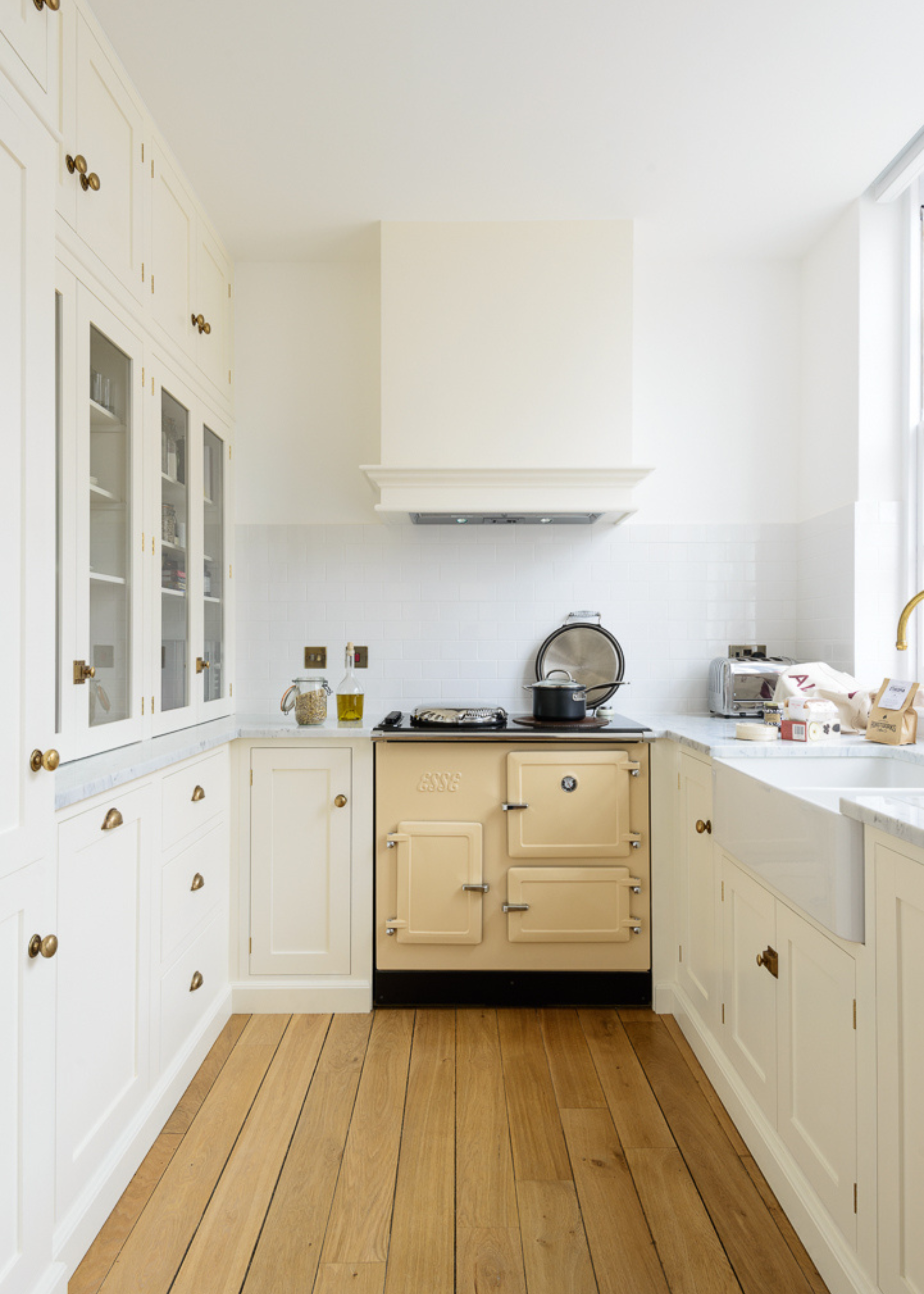 small narrow kitchen with white cabinets and a butter yellow aga stove