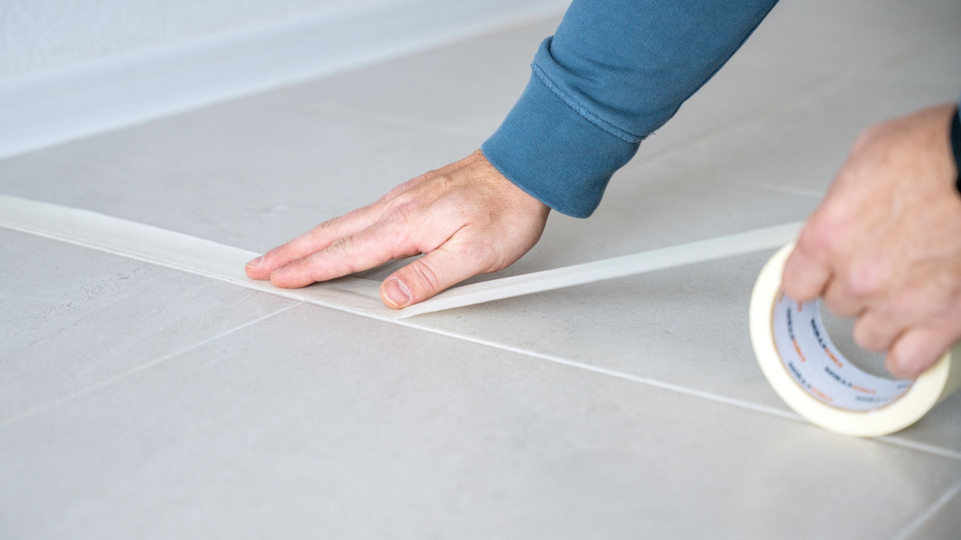 picture of man using masking tape on floors to plan out furniture placement