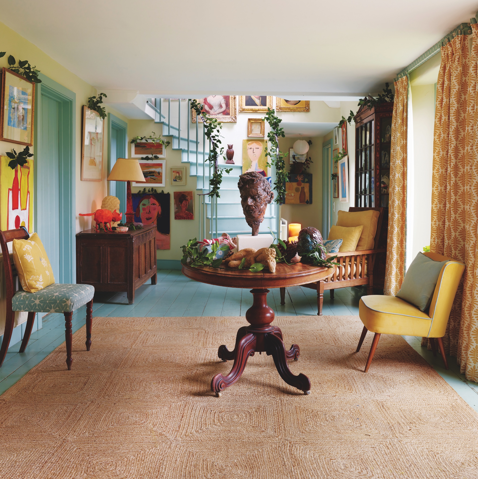 large hallway with pale blue woodwork and a selection of occasional chairs, a wooden trunk and a circular mahogany table