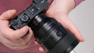 Sony FE 135mm lens attached to a sony camera and held in a pair of hands