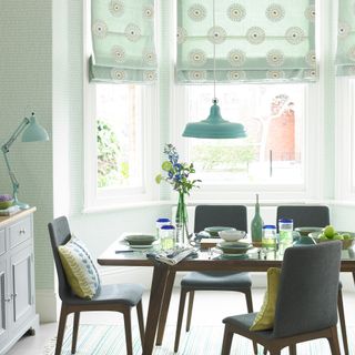 Green dining room with patterned wallpaper and blinds