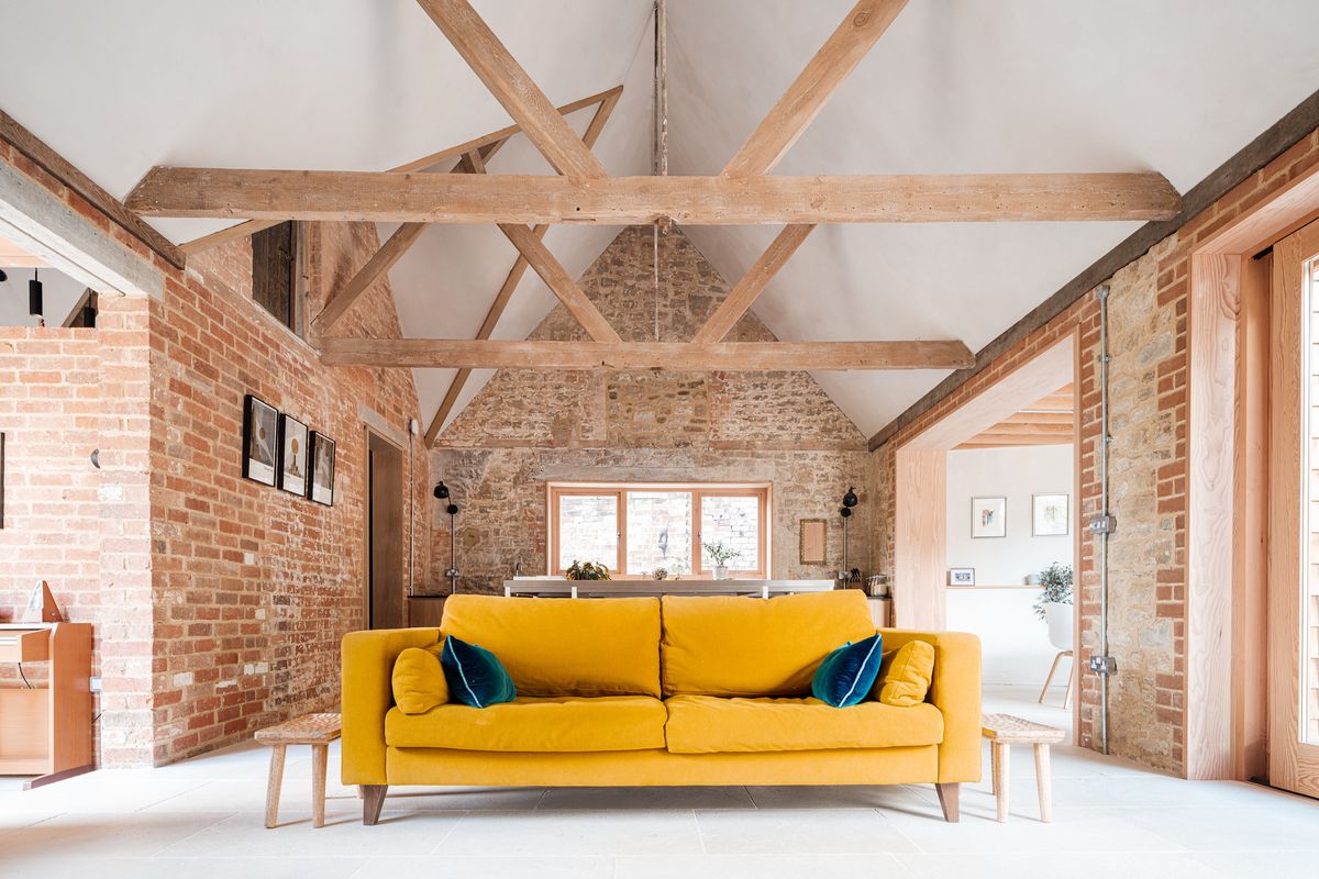 stone living room with exposed beams and yellow sofa