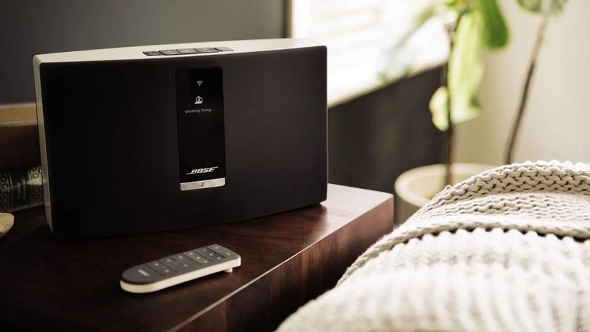 A Bose SoundTouch 20 speaker on a bedside table with its remote control.