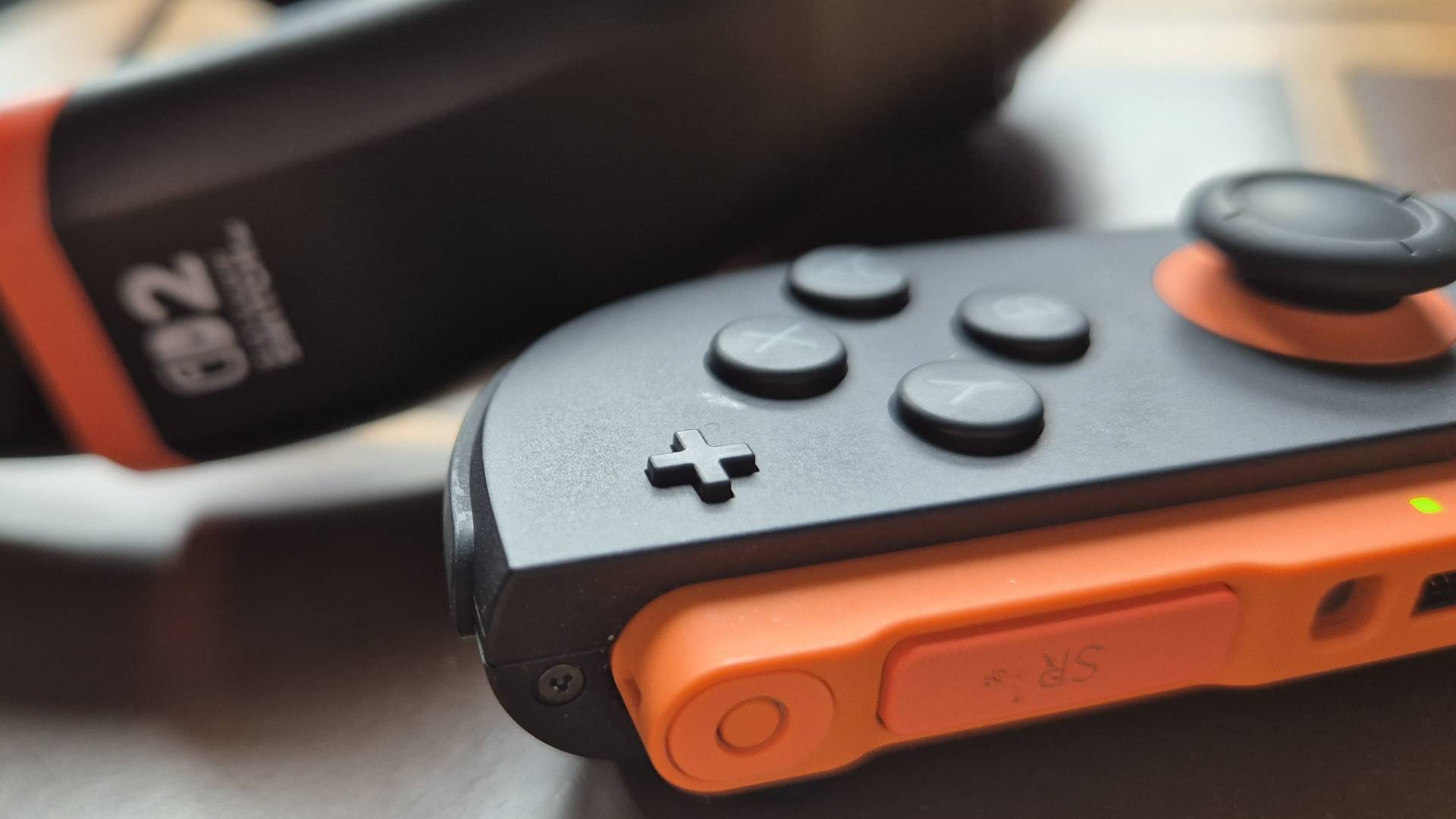 Photo of a close up of the right Joy-Con 2 controller, with the Airlite Fit headset blurred in the background.