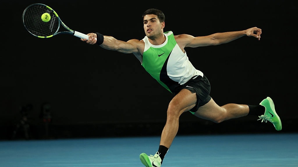 Carlos Alcaraz stretches to hit a forehand in the first round of the Australian Open 2026.