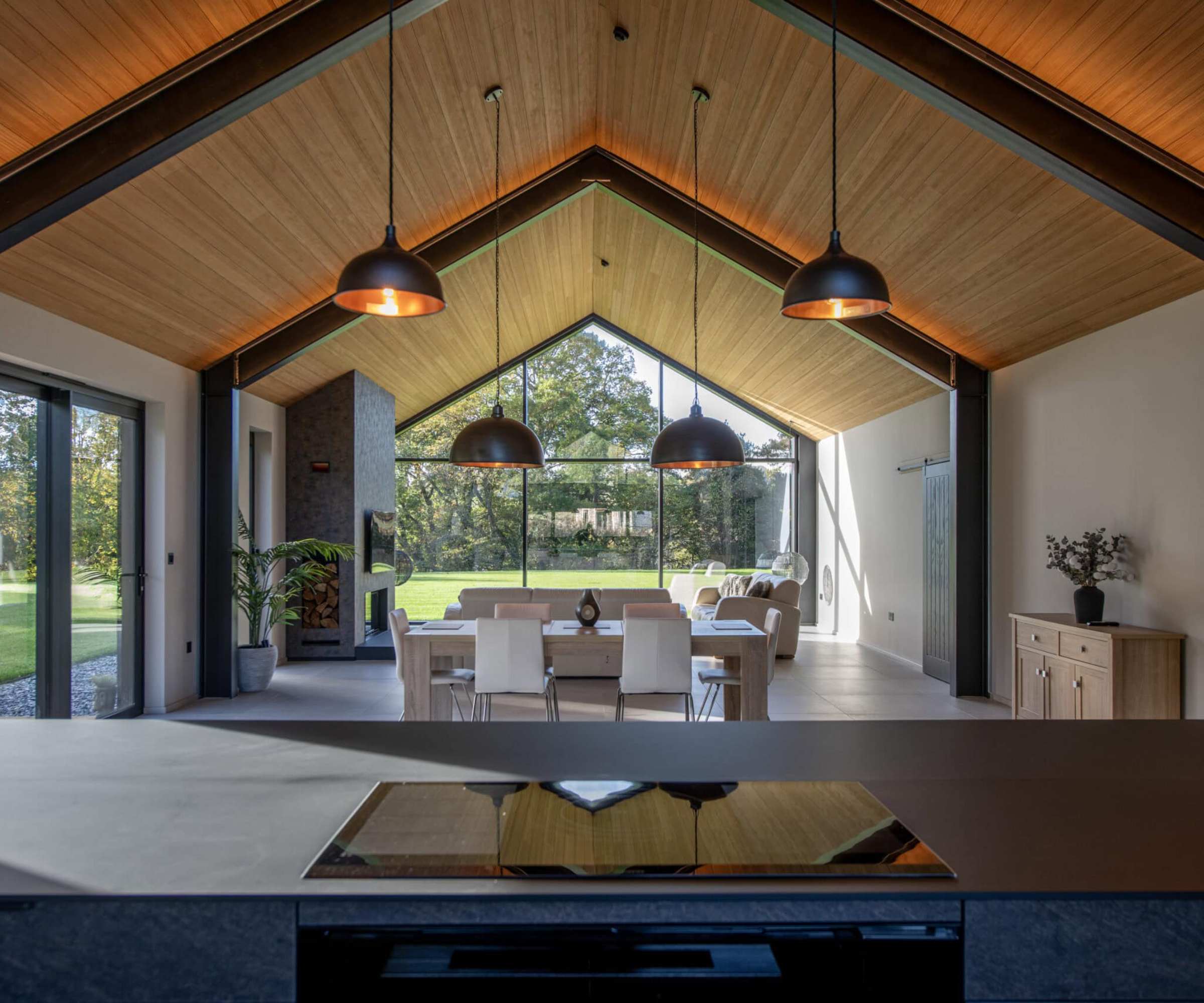 large vaulted ceiling kitchen diner with wooden ceiling, large windows and inset LED lighting in beams