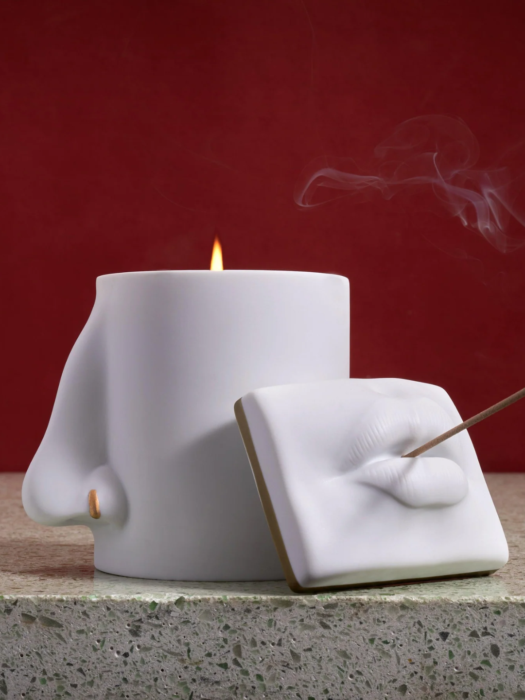 A nose-shaped candle by a lip-shaped incense holder from L'Objet