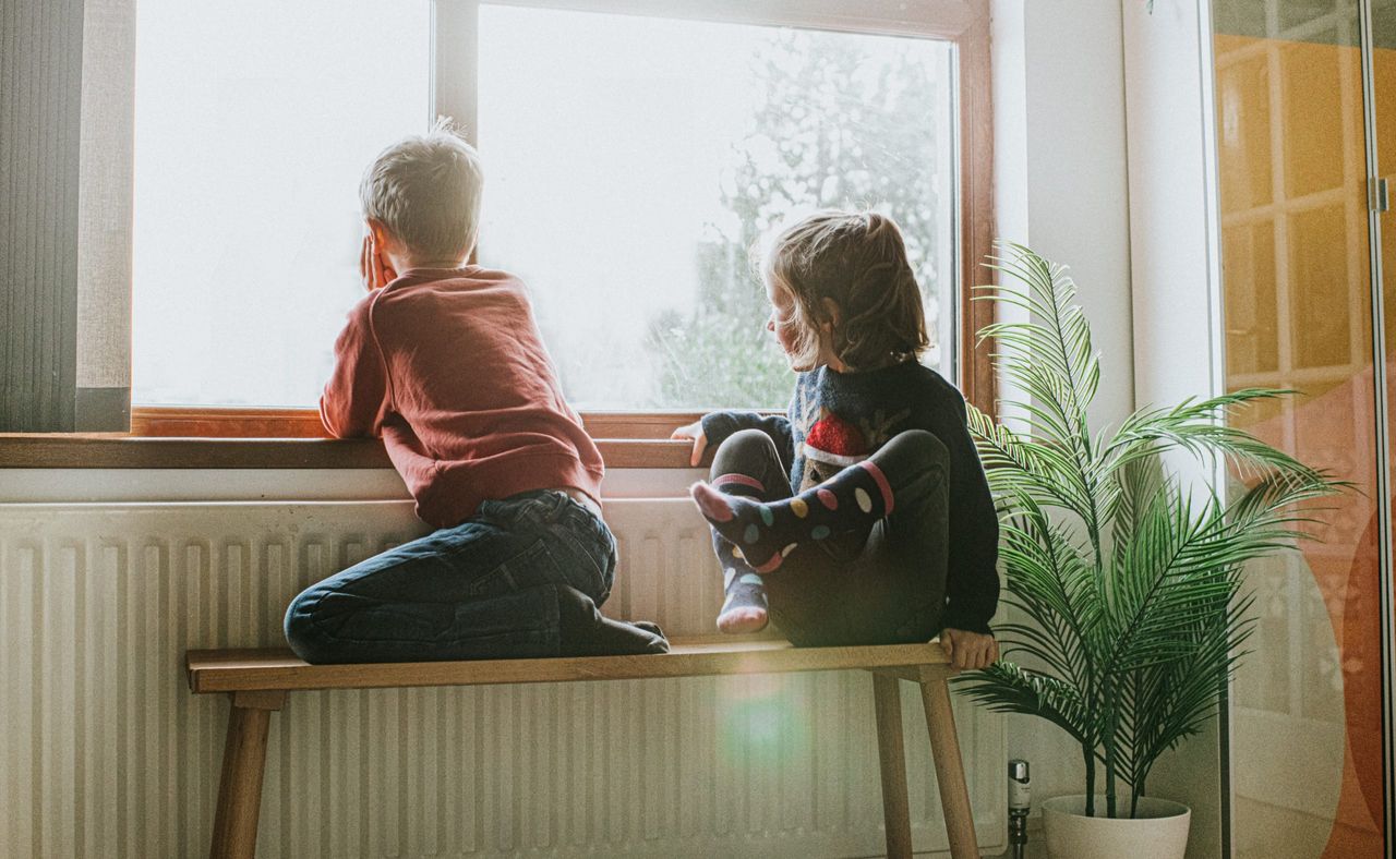 radiator hack stop wasting heat - two children sitting beside radiator