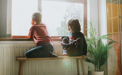 radiator hack stop wasting heat - two children sitting beside radiator