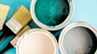 Top down shot of three open paint cans with paintbrushes in background