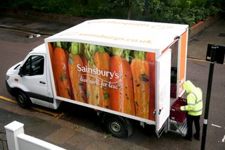Sainsbury's delivery van parked up with delivery driver collecting baskets from the back