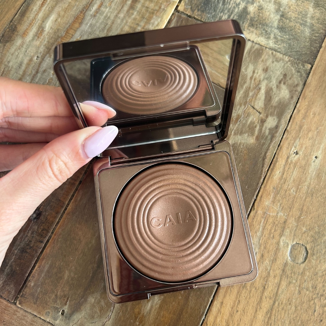 Hand holding the CAIA Glow Bronzer