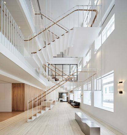 Focussing on a long rectangular wood reception-style desk in a room with a wood floor and wood wall behind the desk