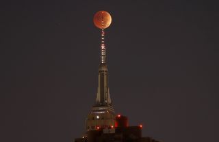 New York City's Empire State Building appears to skewer the blood moon on Nov. 8, 2022. (Photo by Gary Hershorn/Getty Images)