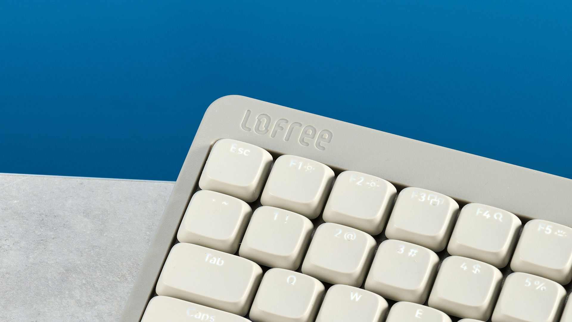 The Lofree Flow Lite84 on a stone surface against a blue background