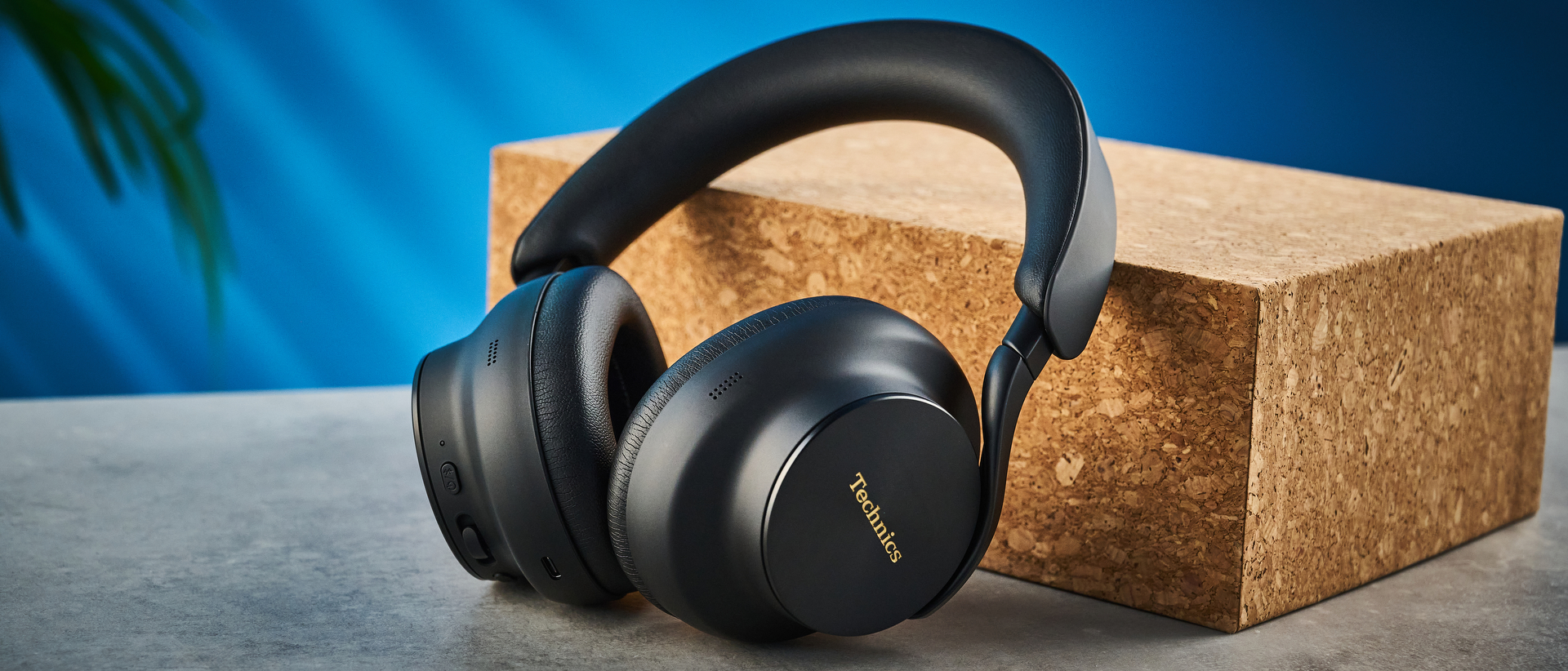 the technics eah-a1000 headphones with a gold technics logo photographed against a blue background