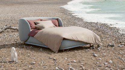 pale blue upholstered bed with bedlinen all within in seaside setting near the ocean