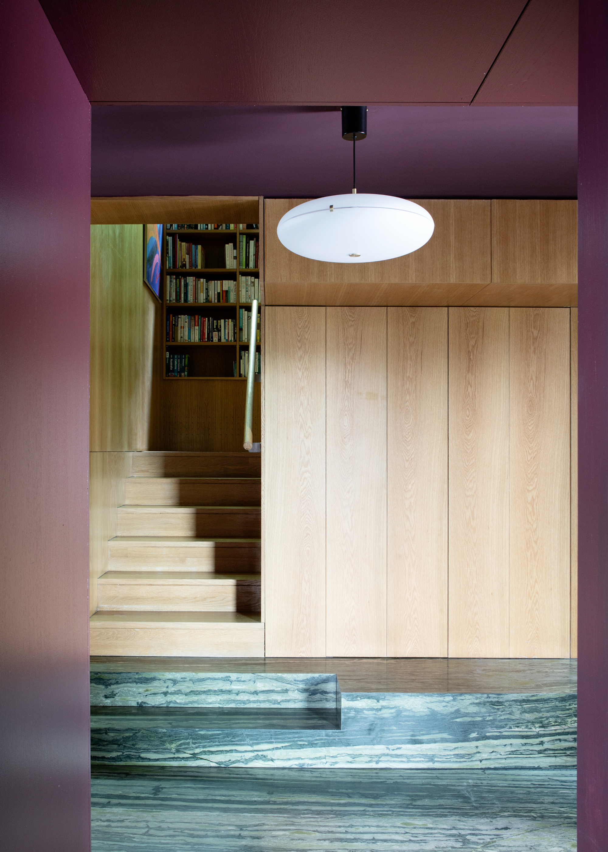 a sleek wooden staircase with three green marble stairs at the bottom