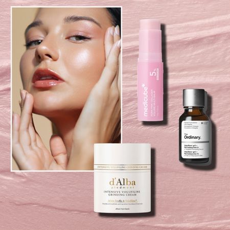 a white woman with glowing skin on a pink cream background next to a white jar of cream with gold writing, a pink tube of serum, and an amber jar with a white label